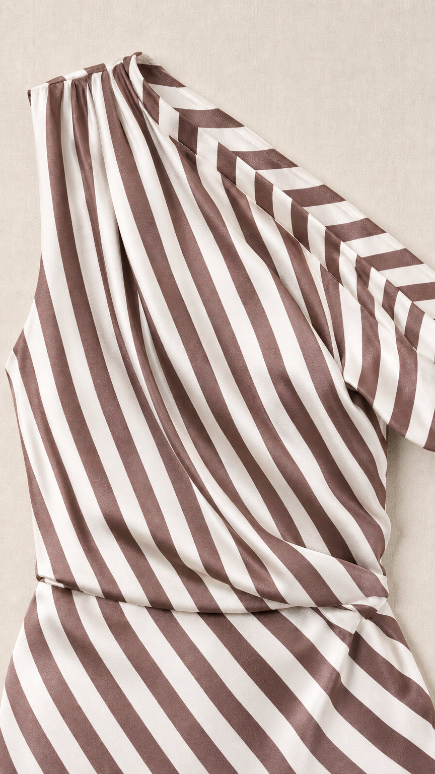 Close-up detail of fabric and one-shoulder strap of brown striped dress