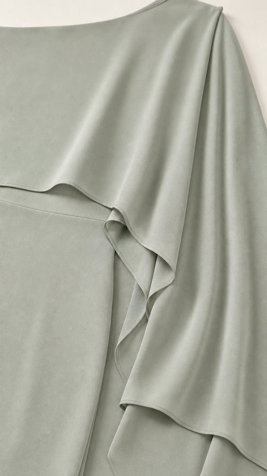 Close-up detail of smooth fabric and draped cape overlay
