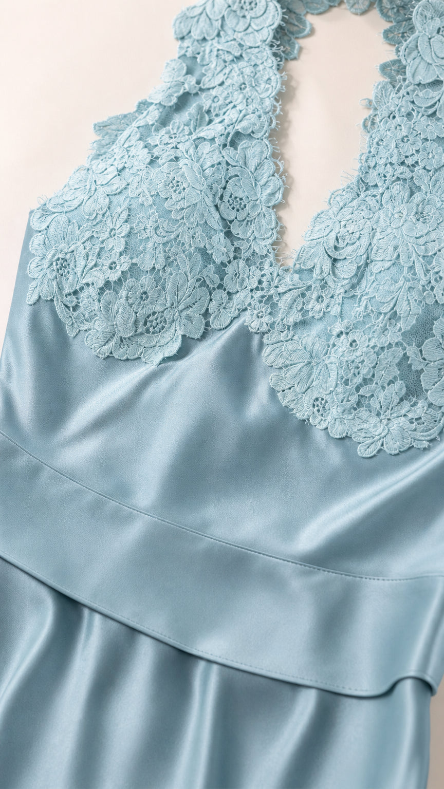 Close up view of intricate floral lace bodice and smooth blue satin fabric