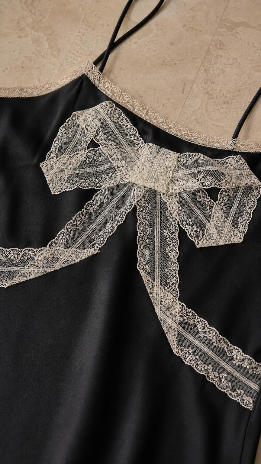 Close-up detail of lace bow and neckline on black dress