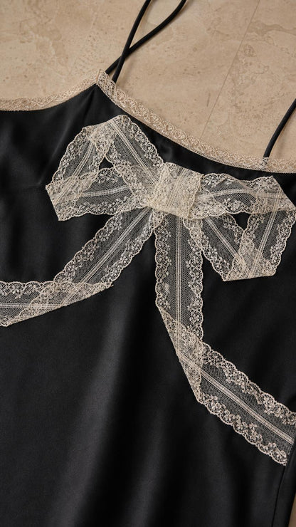 Close-up detail of lace bow and neckline on black dress