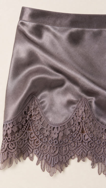 Close-up detail of smooth satin fabric and scalloped floral lace trim hemline
