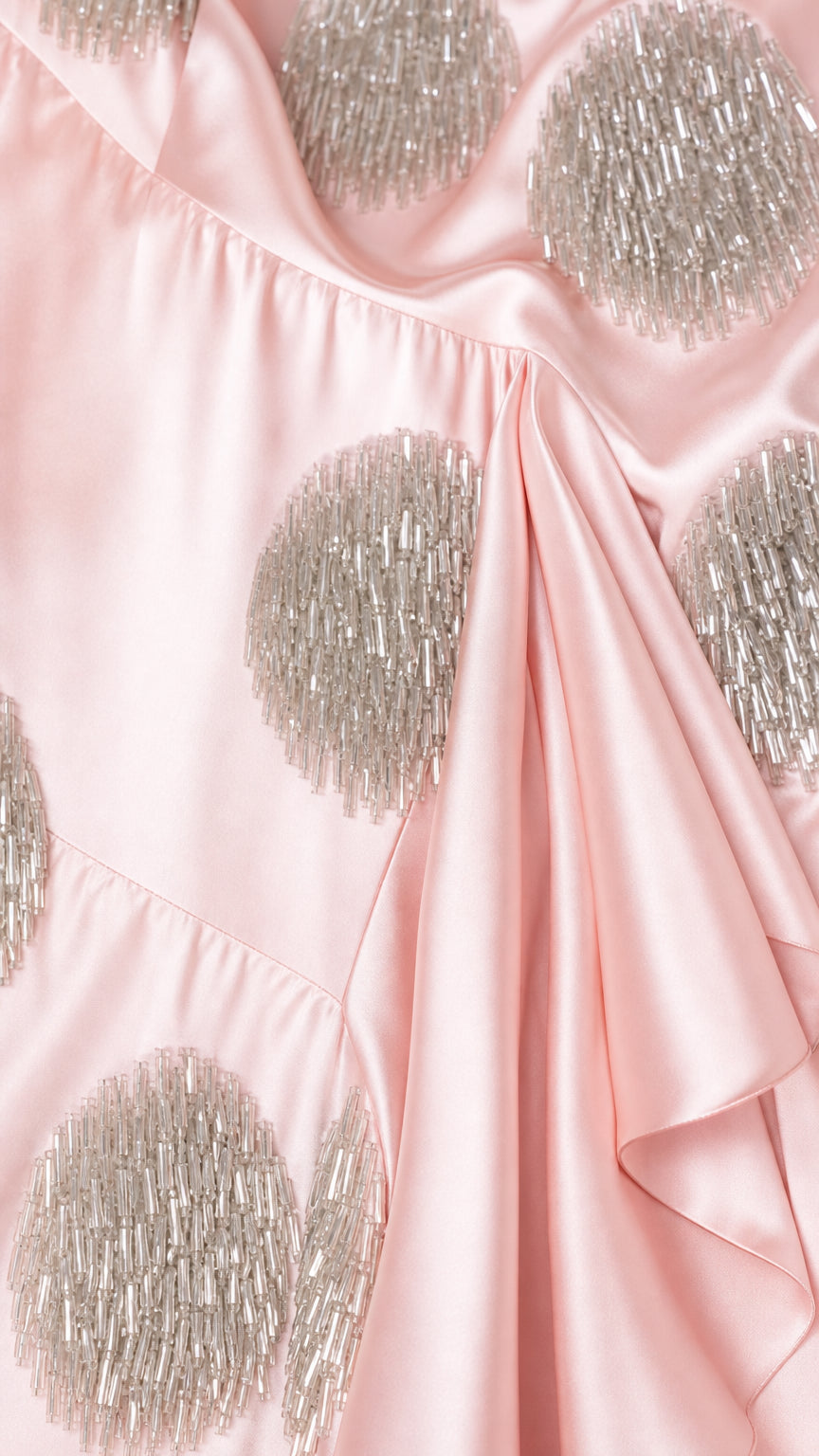 Close-up detail of textured sequin polka dot pattern on pink satin fabric