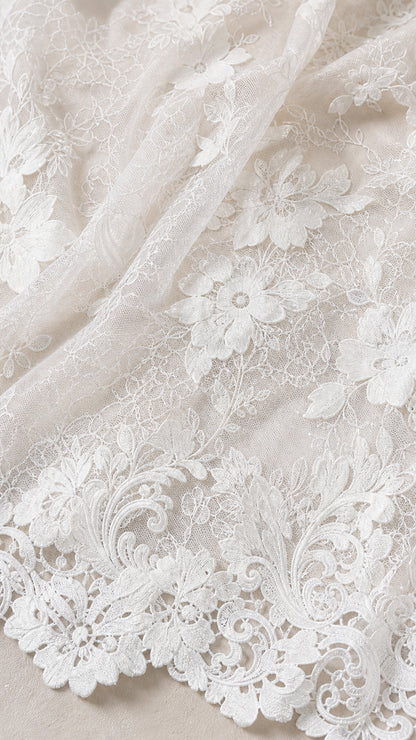 Close-up detail of white floral lace fabric and scalloped hem