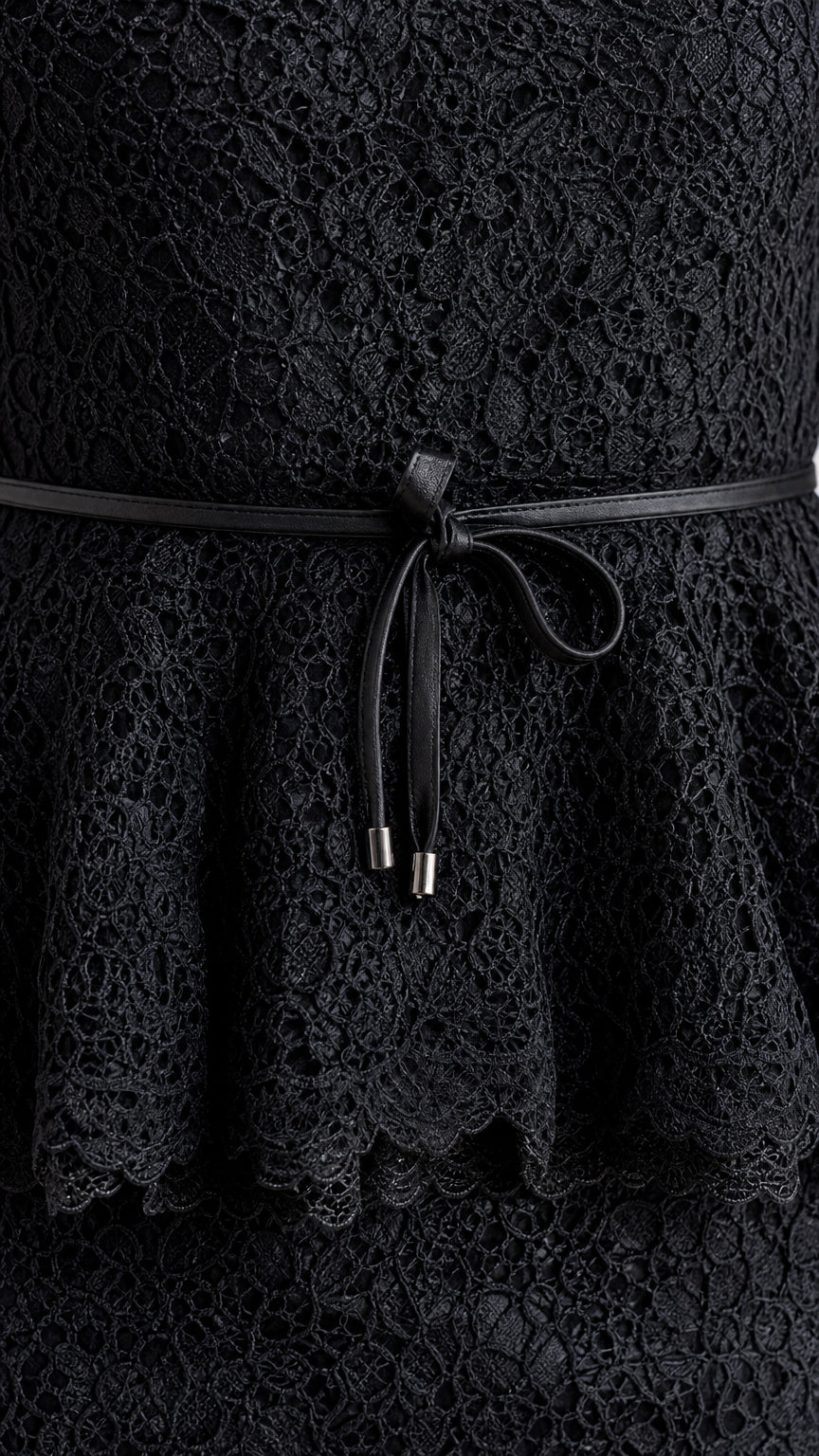 Close-up detail of black lace fabric, peplum frill, and slim tie belt