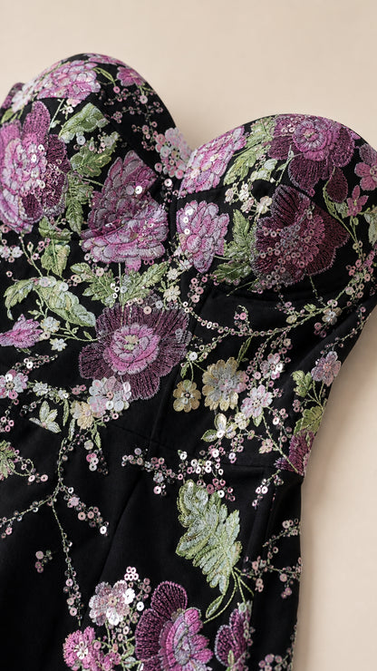Close-up detail of sweetheart neckline and sequin floral embroidery on black evening dress