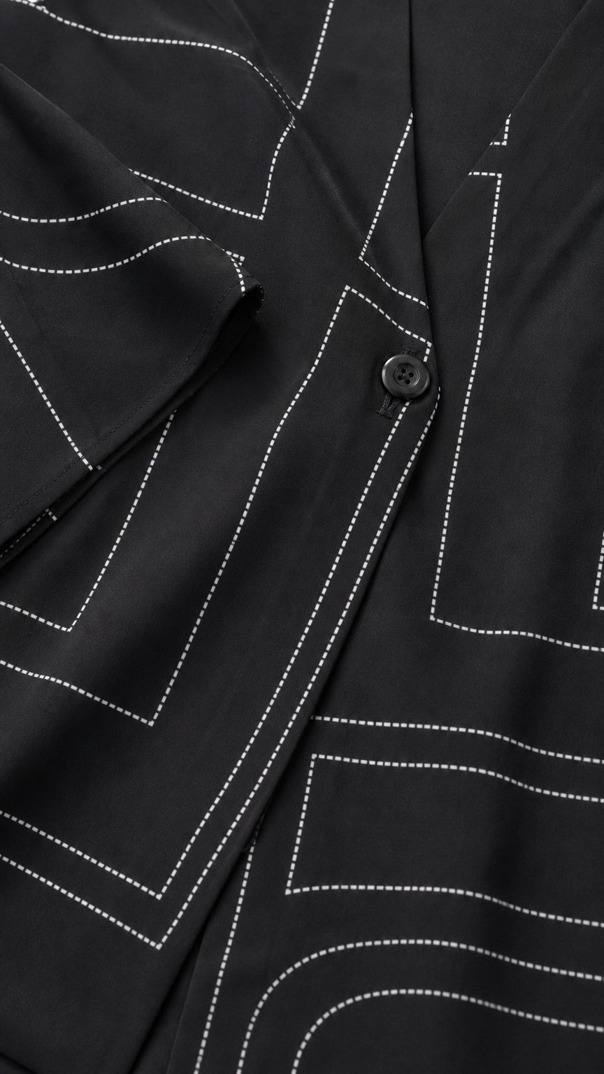 Close-up detail of white geometric line print and button closure on black fabric