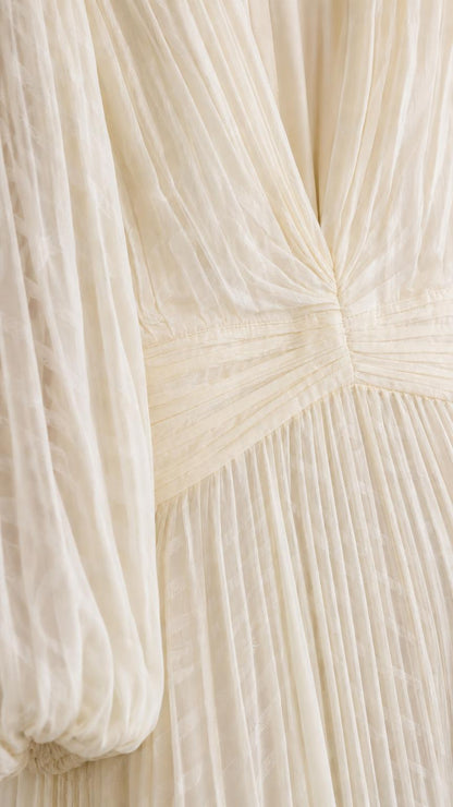 Close up of textured pleats and V-neck on cream maxi dress