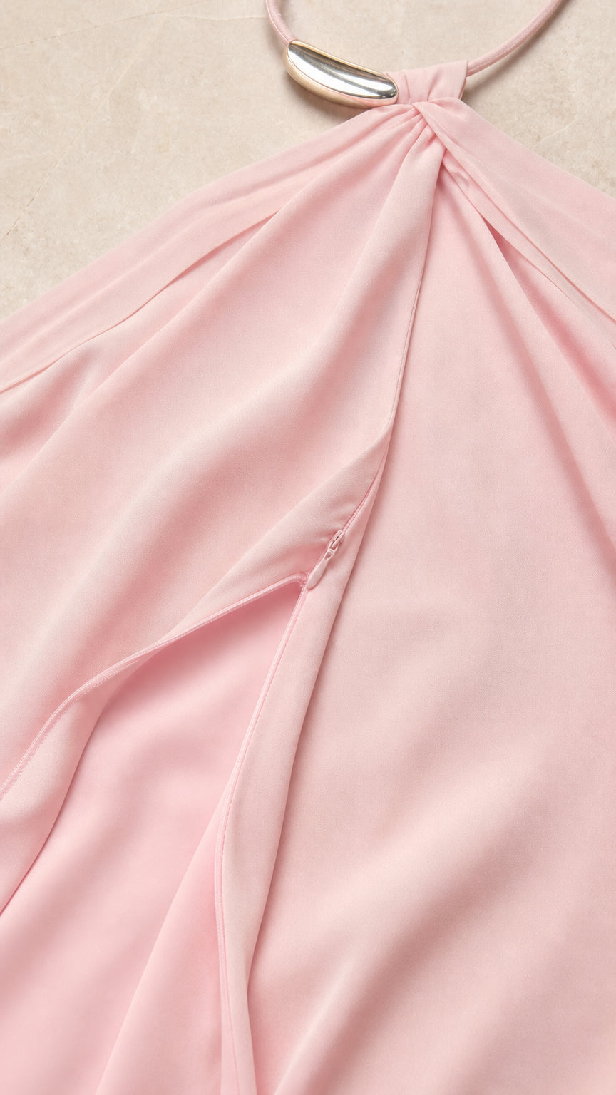 Close-up detail of halter neckline and metallic hardware on pink dress