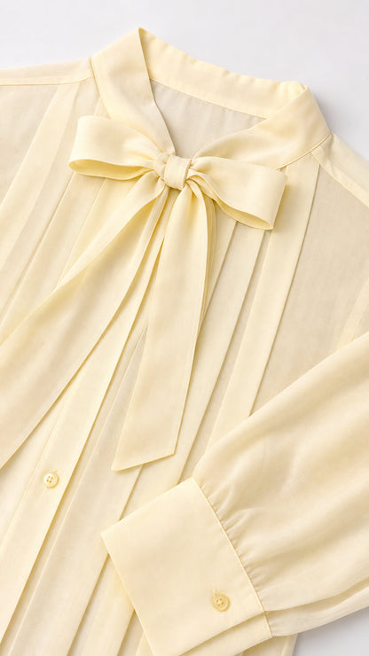 Close-up detail of neck bow and sleeve cuff on cream dress