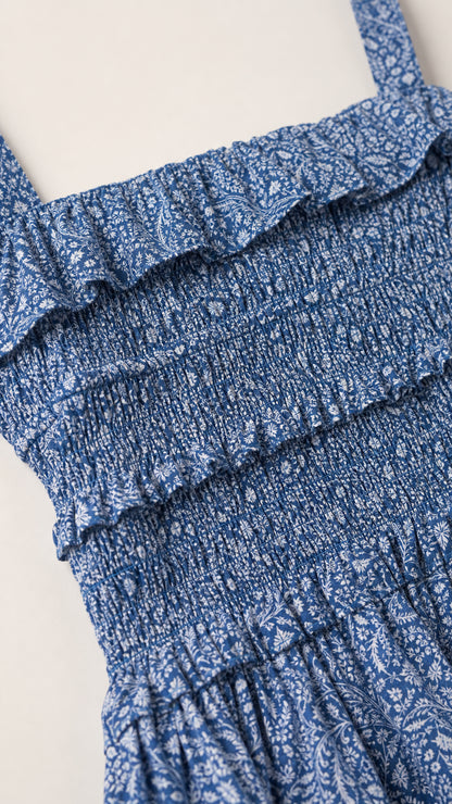 Close-up of smocked bodice and ruffle trim detail on blue floral dress
