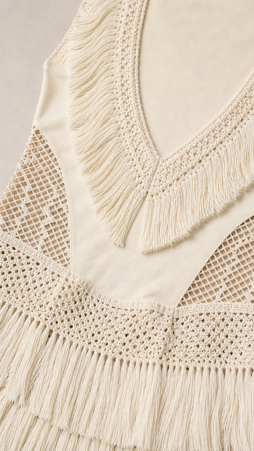 Close-up detail of V-neck fringe and crochet panels on cream dress