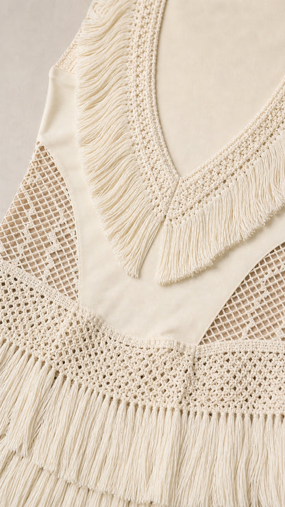 Close-up detail of V-neck fringe and crochet panels on cream dress