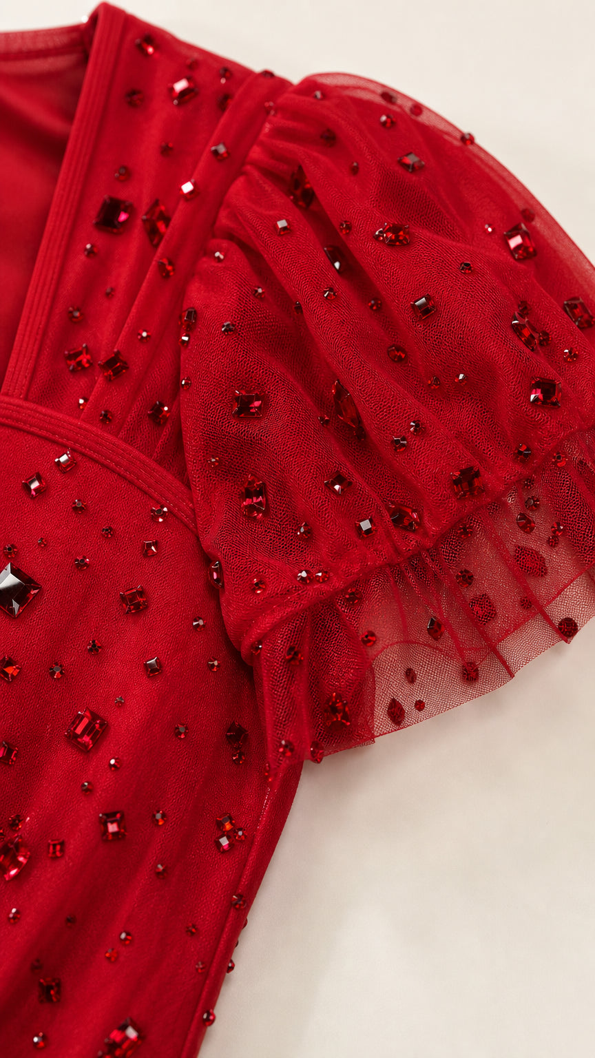 Close-up detail of ruby red sheer mesh flutter sleeve with shimmering beadwork and rhinestones