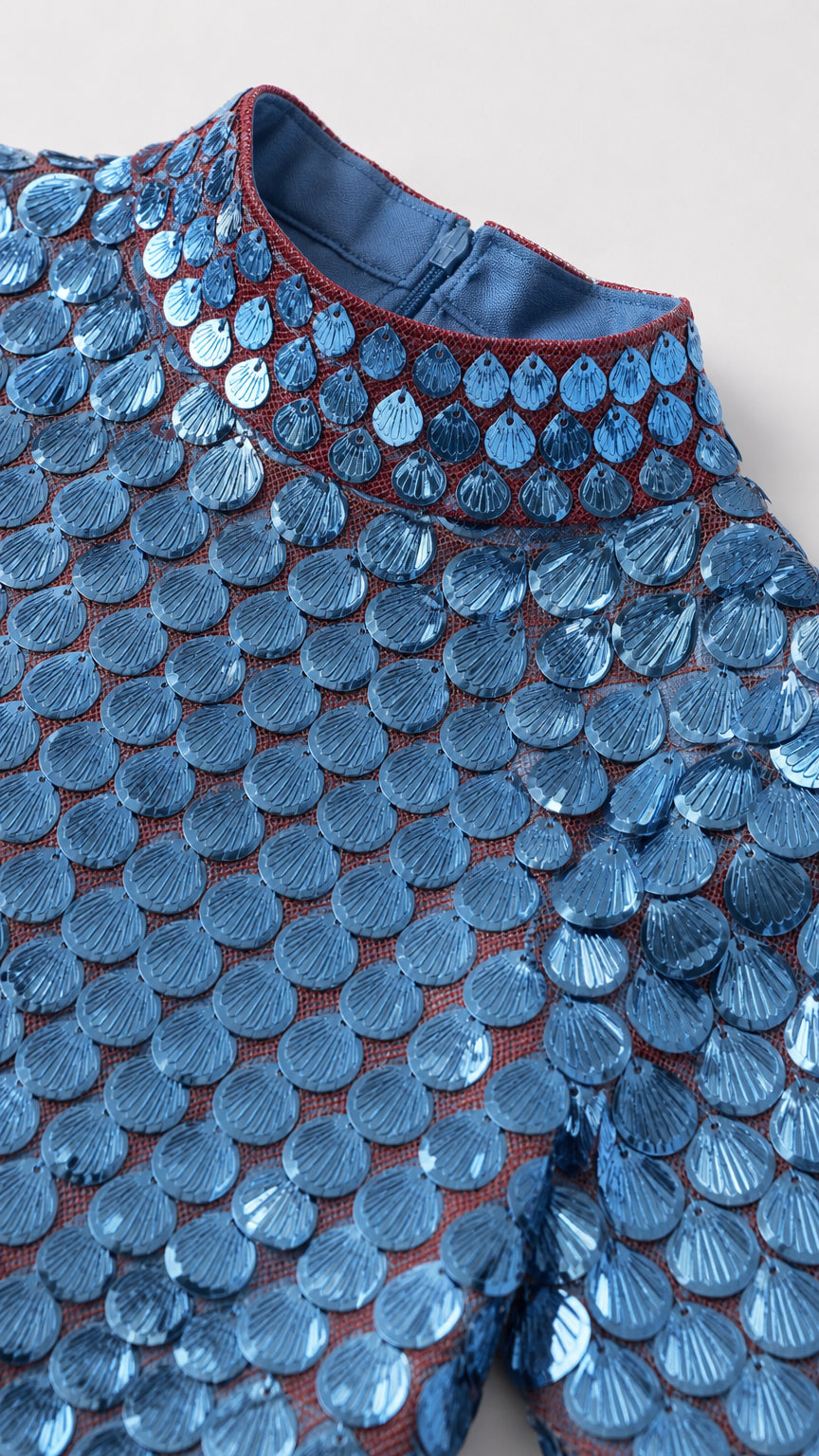 Close-up detail of blue scalloped scale paillettes and mock neckline