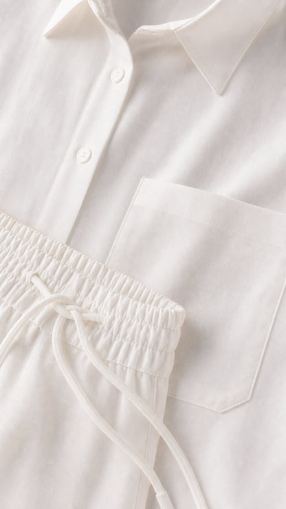 Close-up detail of white button-down shirt collar, pocket, and drawstring pants