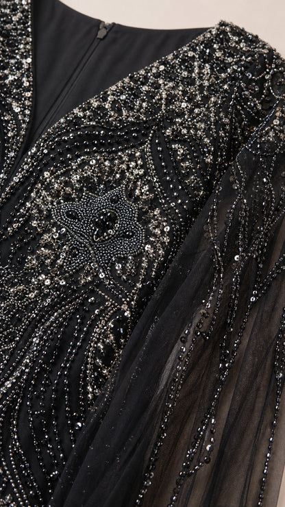 Close-up detail of intricate silver and black sequin embroidery on mesh fabric