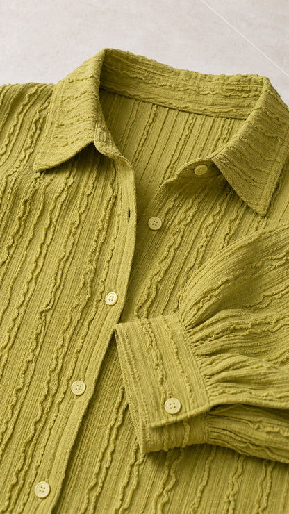 Close-up detail of textured fabric, collar, and buttons on olive green shirt