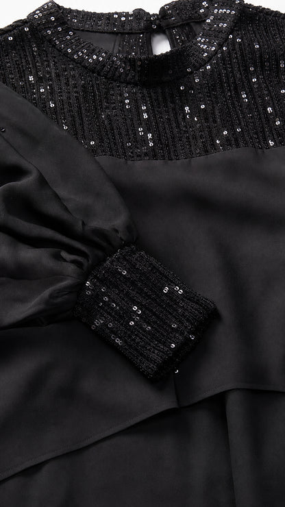 Close-up of black sequin mock neck and embellished cuffs