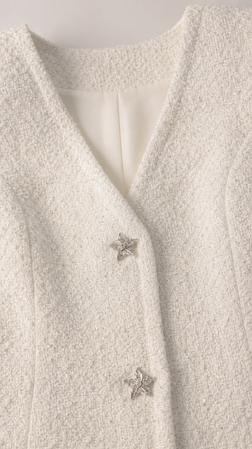 Close-up of white tweed fabric and star buttons