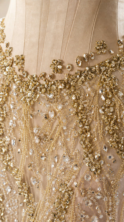 Close-up of intricate gold beadwork and crystal embellishments on evening gown