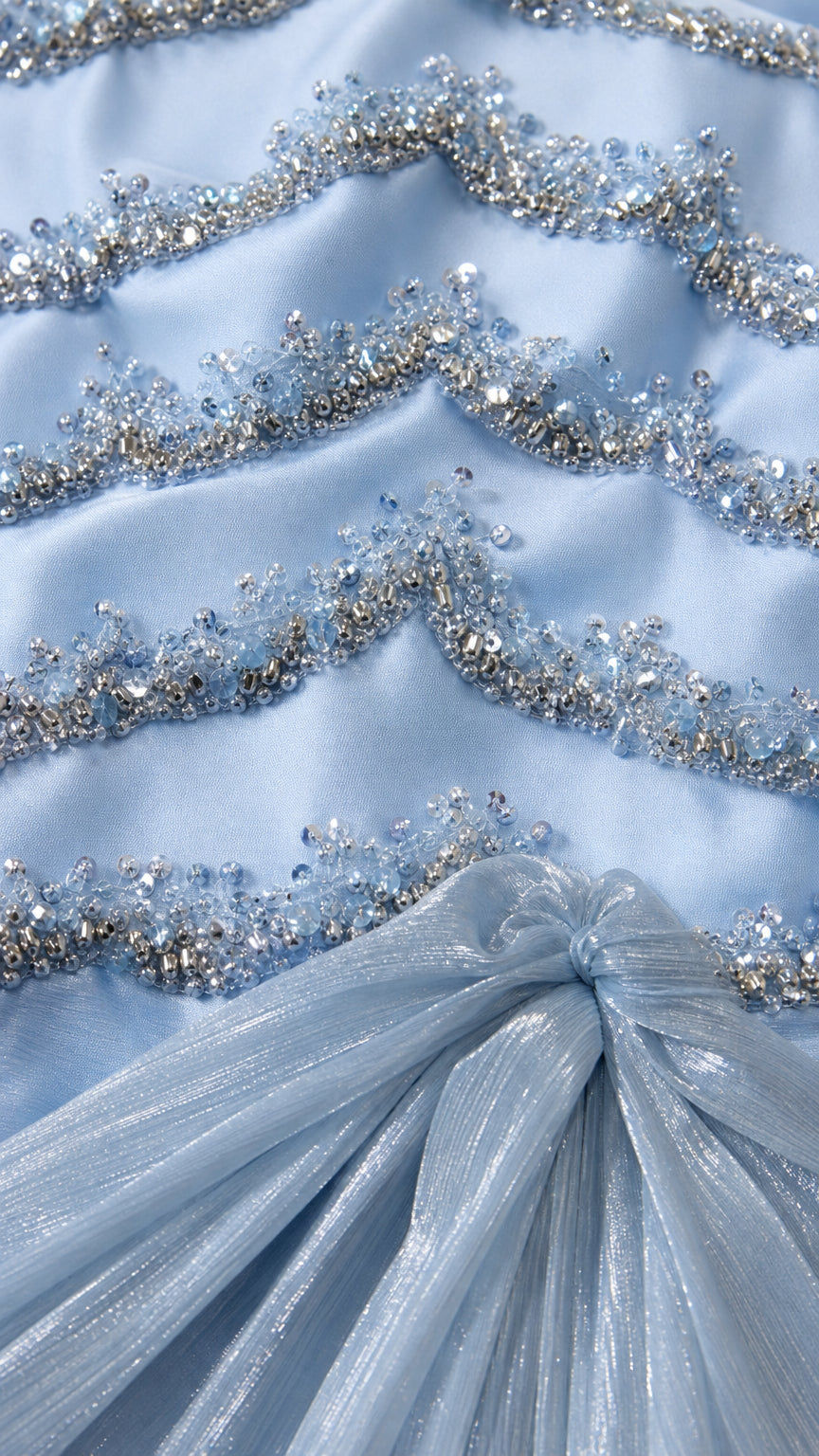 Close-up detail of silver beadwork and gathered shimmer overlay fabric