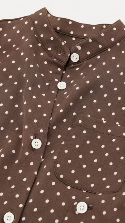 Close-up of fabric, buttons, and collar details on brown polka dot top