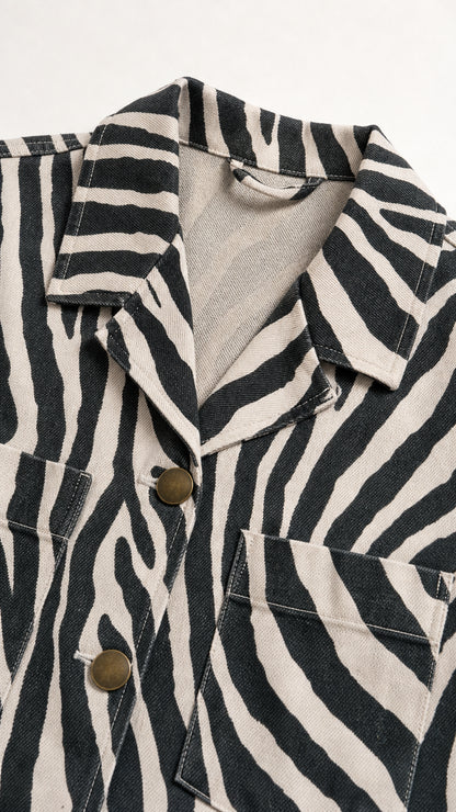 Close-up detail of textured fabric, notch collar, buttons, and pocket on zebra print shirt