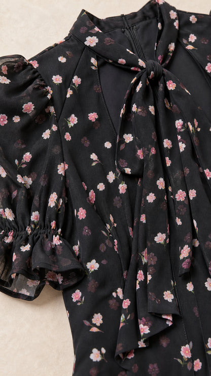 Close-up detail of neck tie cutout collar and puff sleeve on black floral dress