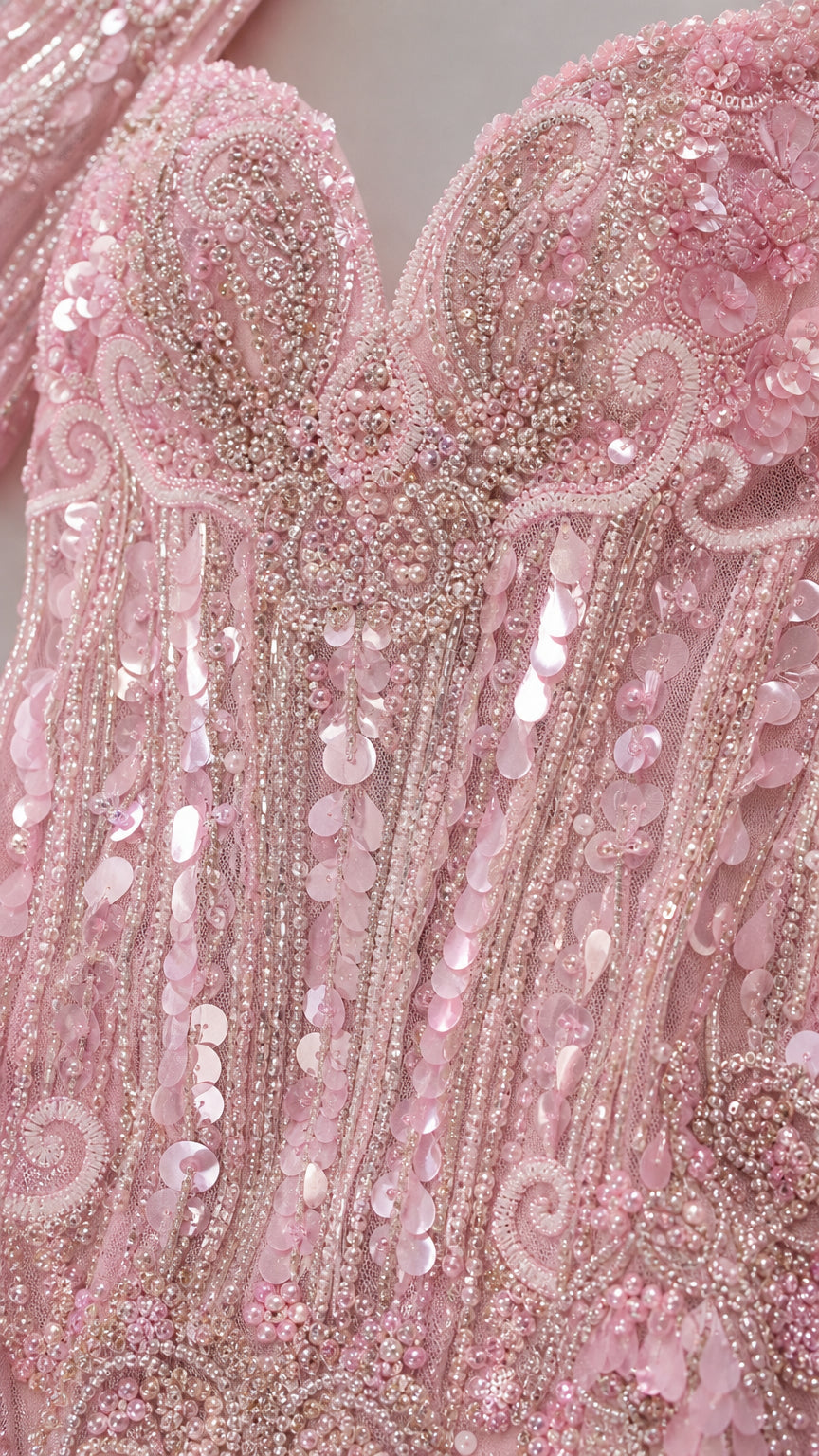 Close-up detail of intricate blush pink sequin, pearl, and beaded scrollwork embroidery