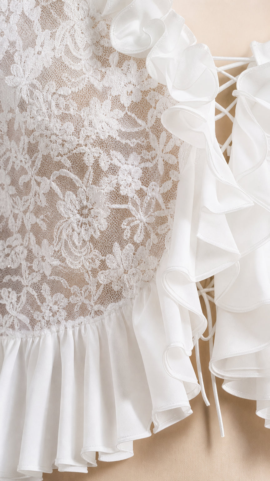 Close-up detail of white floral lace texture, layered ruffle edges, and lace-up front tie