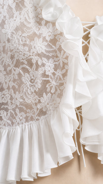 Close-up detail of white floral lace texture, layered ruffle edges, and lace-up front tie