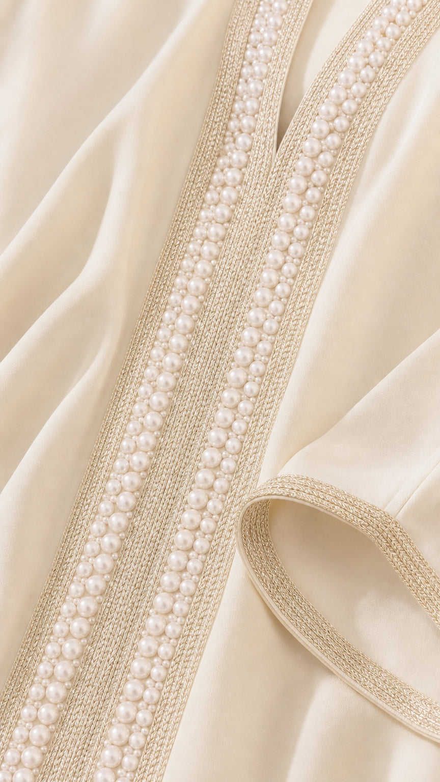 Close-up detail of faux pearl embroidery and trim on the kaftan