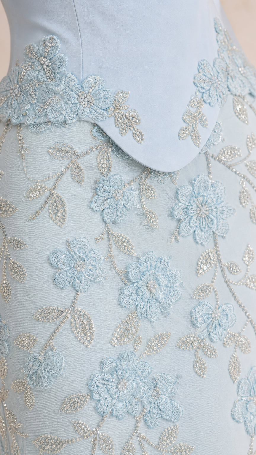 Close-up of floral embroidery and beading detail on light blue dress