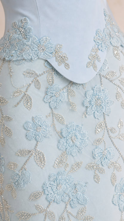Close-up of floral embroidery and beading detail on light blue dress