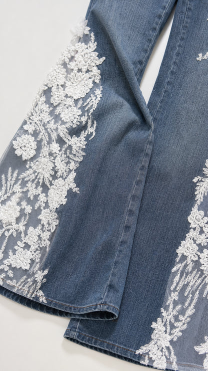 Close-up of intricate white floral lace appliques on denim hem