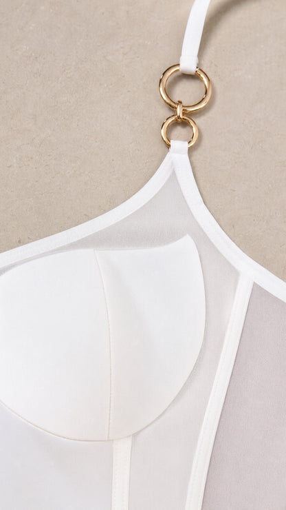 Close-up detail of white dress bodice showing gold-tone interlocking rings and sheer mesh cups
