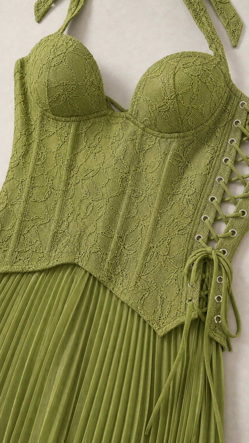 Close-up detail of green lace corset bodice with side lace-up grommets and pleated skirt