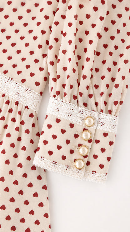 Close-up of pearl button cuffs and lace trim on heart print sleeve