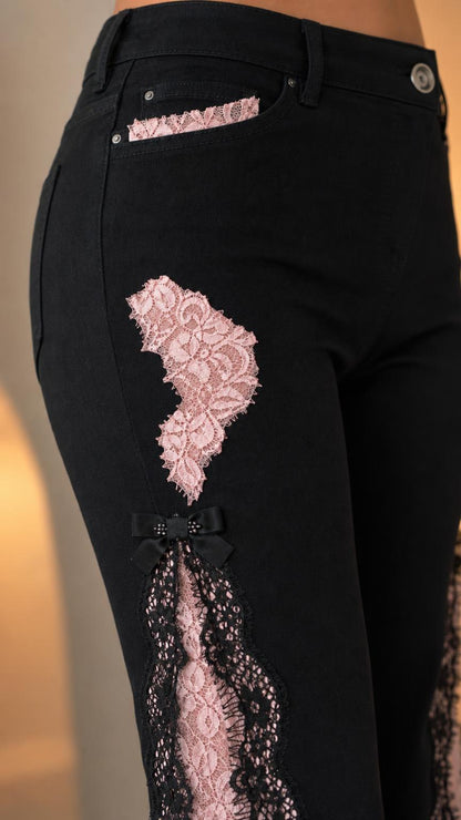 Close-up of black denim pants showing pink lace pocket detail and bow accent