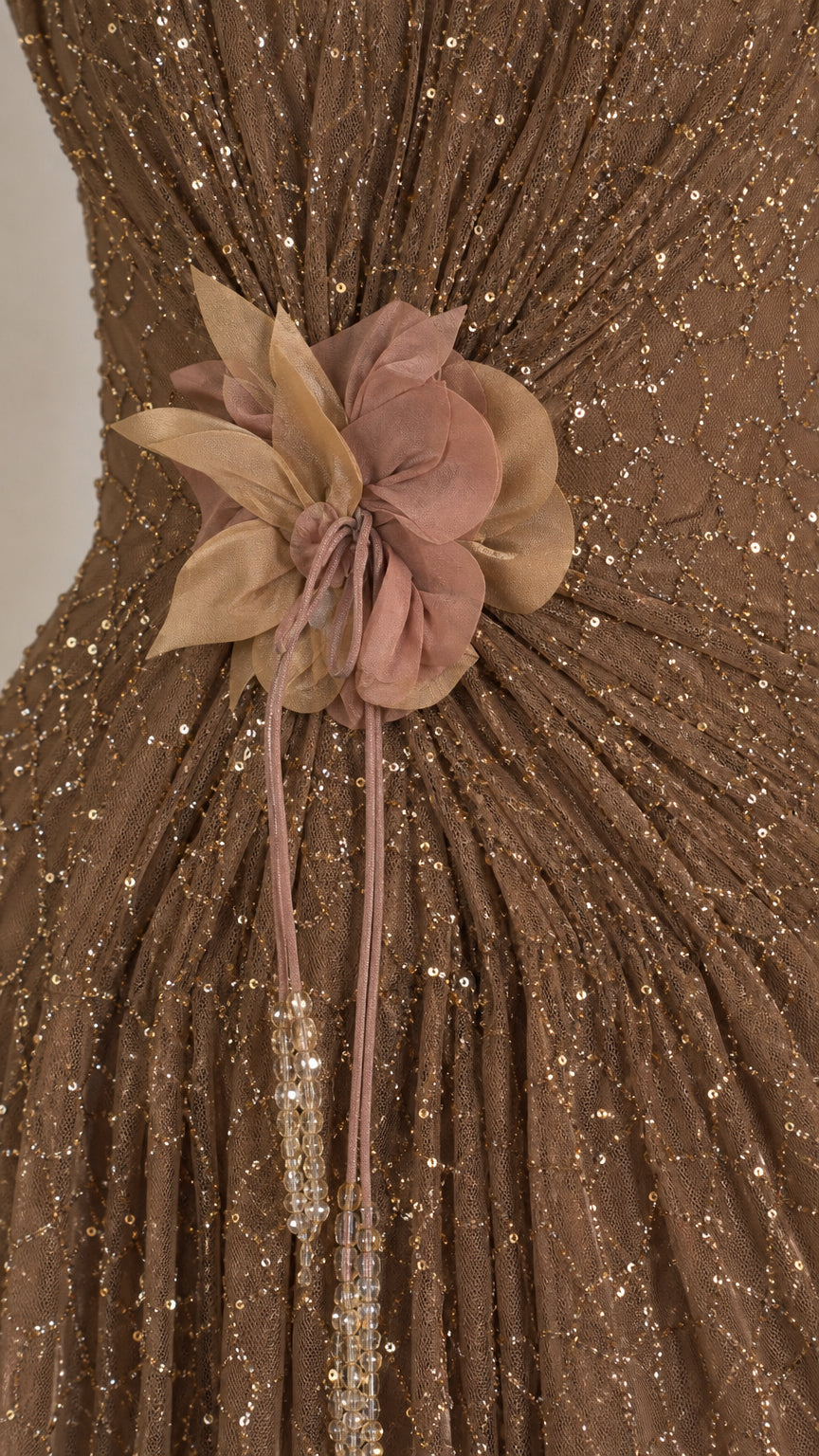 Close-up detail of fabric flower and sequin texture on bronze gown