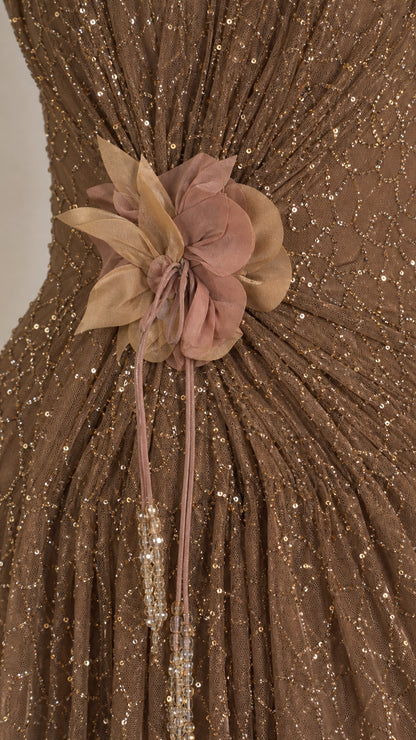 Close-up detail of fabric flower and sequin texture on bronze gown