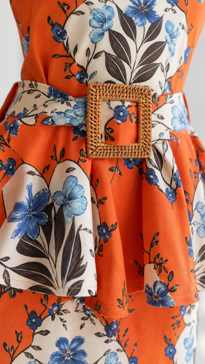 Close-up detail of the woven square buckle belt and floral pattern on orange dress