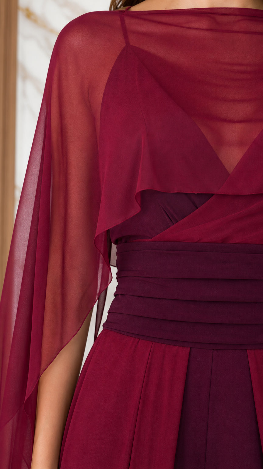 Close up of cape sleeves and pleated waist on burgundy jumpsuit