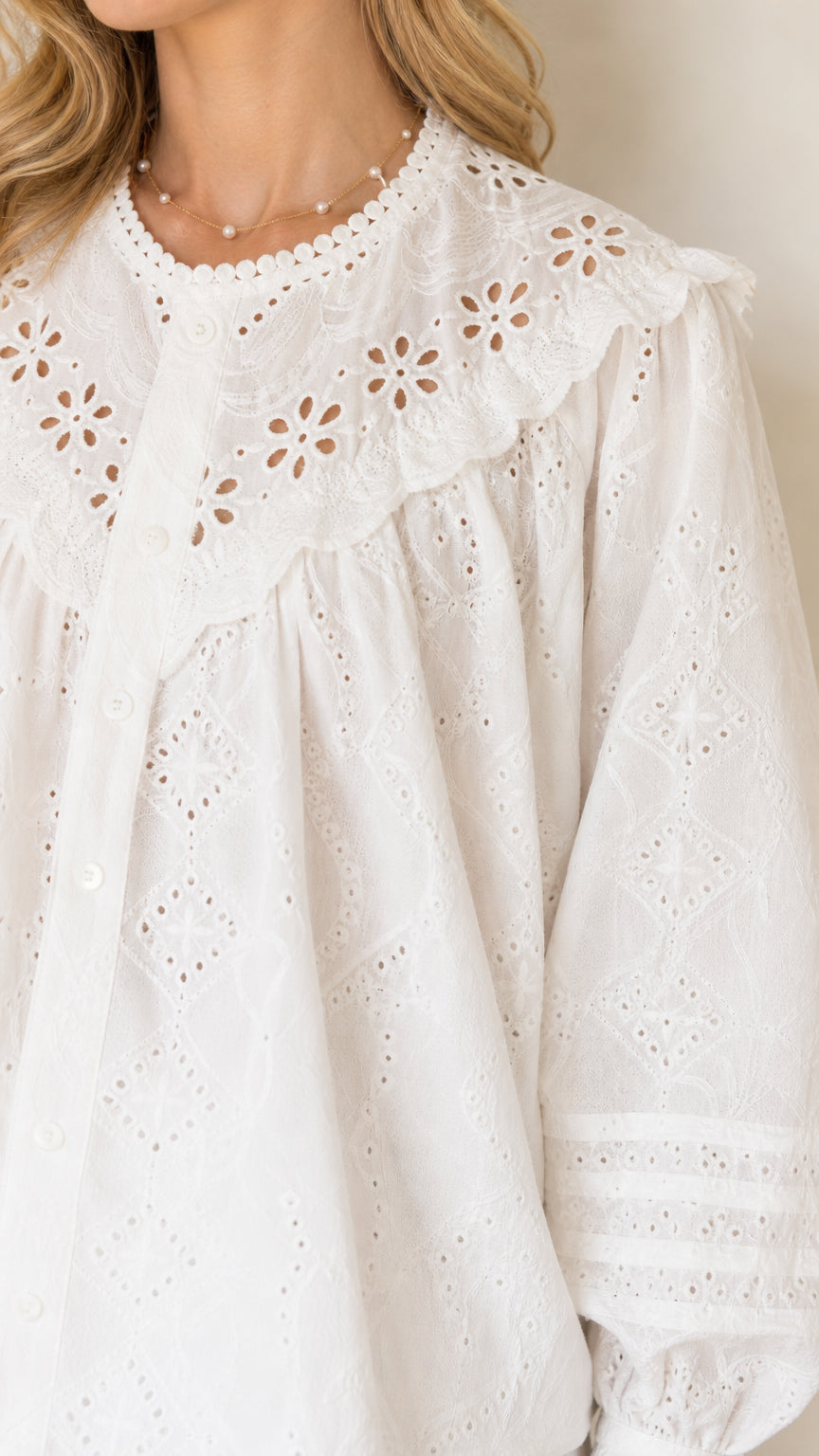 Close-up of white eyelet blouse showing detailed lace embroidery and ruffled yoke