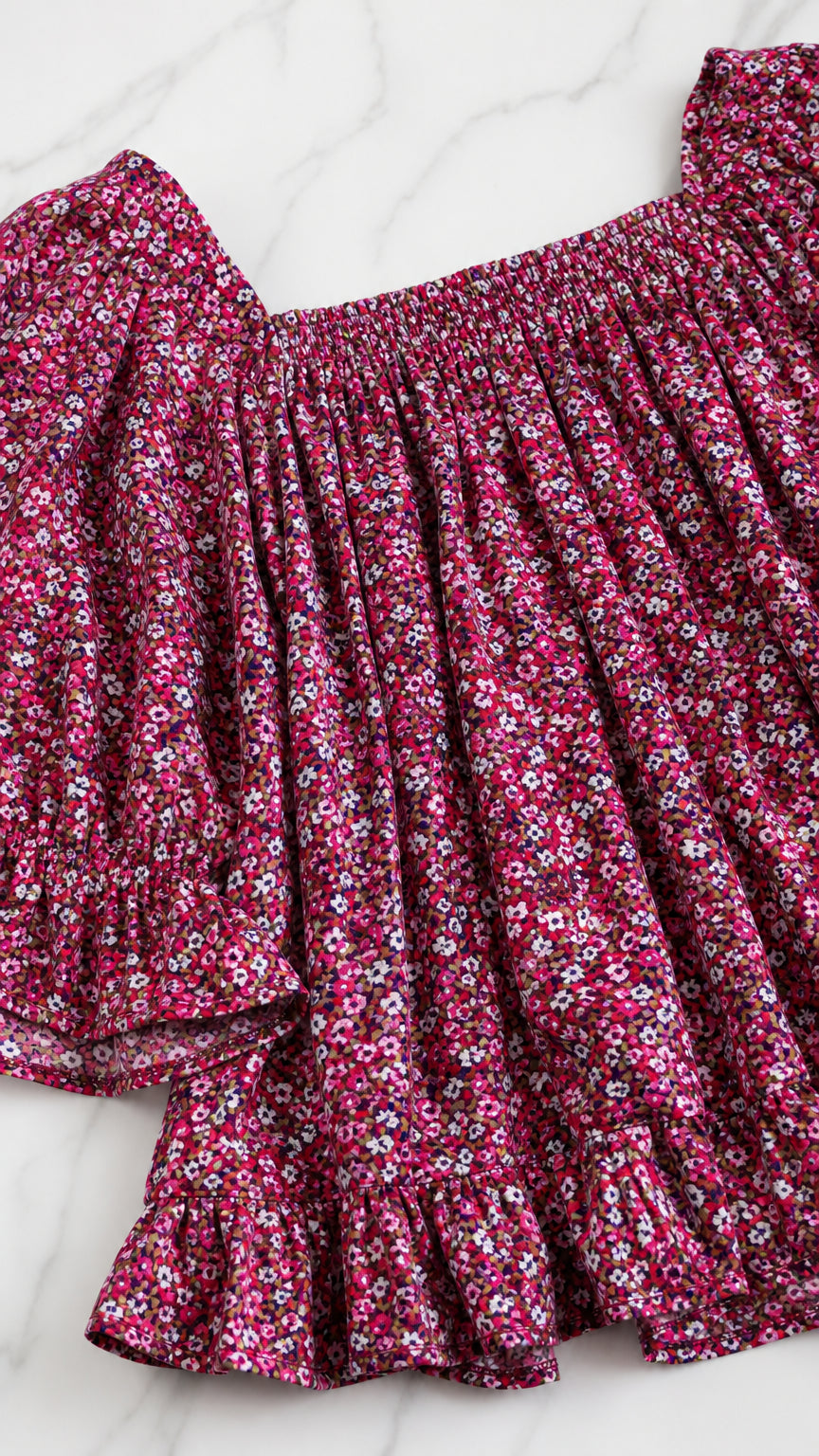 Close-up detail of shirred neckline and ruffled sleeve of magenta ditsy floral top