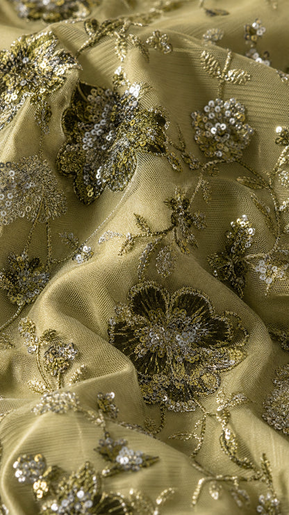 Close-up of sage green fabric texture with floral embroidery and sequins