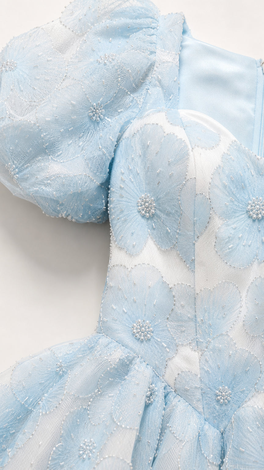 Close up of textured floral jacquard fabric on light blue dress