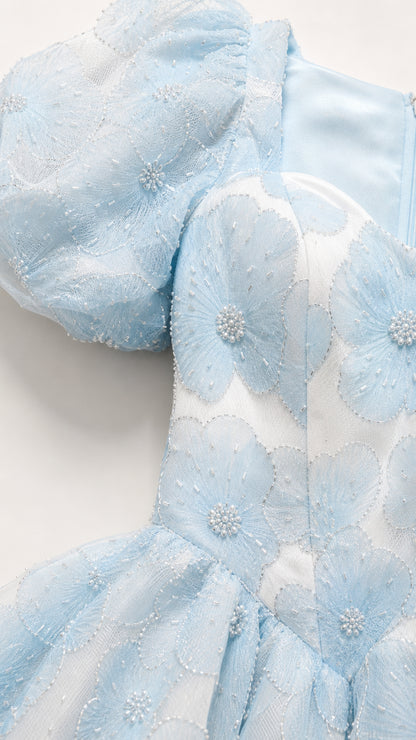 Close up of textured floral jacquard fabric on light blue dress