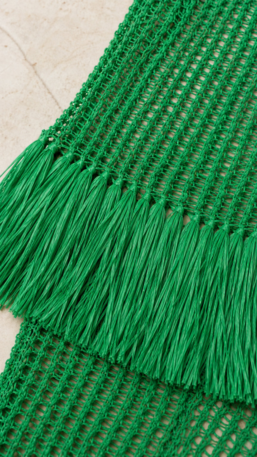 Close up of green open knit texture and fringe